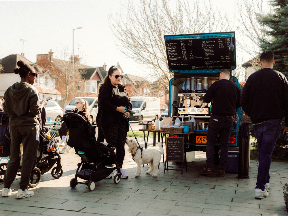 Charlie and Abbi, founders of Roaming Roast, beside their blue Piaggio Ape coffee van