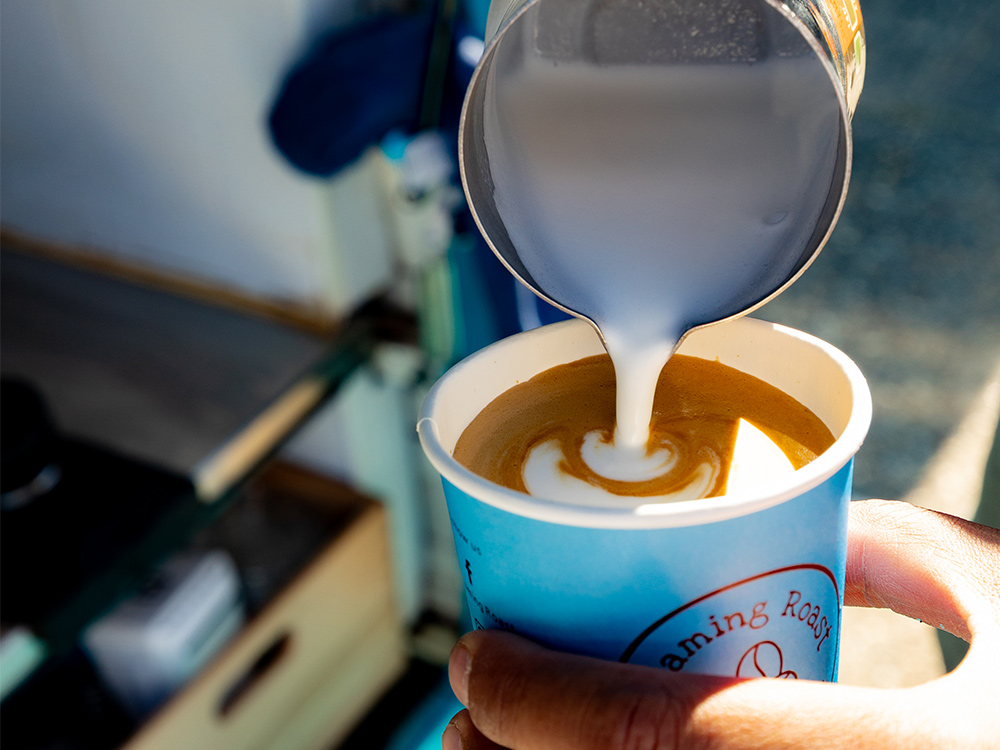 Milk being poured into a freshly made Roaming Roast coffee